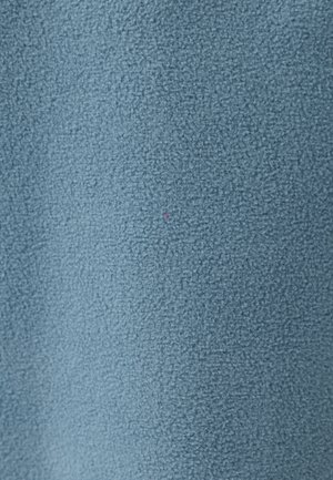 Zacht, gestructureerd lichtblauw stoffen oppervlak met een klein, vaag roze draadje zichtbaar dichtbij het midden.