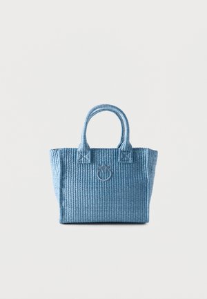 Piccola borsa intrecciata blu con due manici e un emblema circolare sul davanti, su uno sfondo chiaro uniforme.