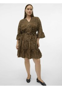 Abito leopardato in tessuto leggero, con scollatura a V, maniche a campana, gonna a strati e vita legata. Abbinato a scarpe nere.