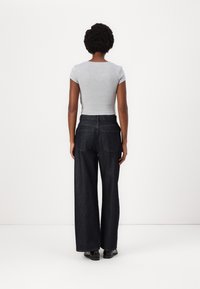 Grå kortermet tettsittende topp kombinert med høyt liv og vide mørke denimjeans. Glatt tekstur og klassisk femlommers design.