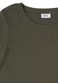 Haut en tricot côtelé vert olive avec encolure ronde et une étiquette blanche inscrite "CECIL" au col.