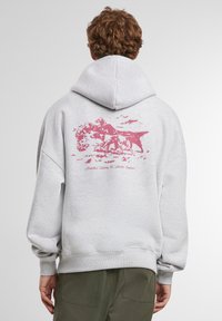 Šedá mikina s kapucňou a veľkým ružovým grafickým dizajnom zvierat na chrbte. Obsahuje rebrované manžety a spodný lem, vyrobená z mäkkej tkaniny.