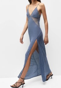 Robe longue bleu profond avec décolleté en V, détails en dentelle et fente haute. Caractérisée par des bretelles fines et un tissu texturé au design fluide.
