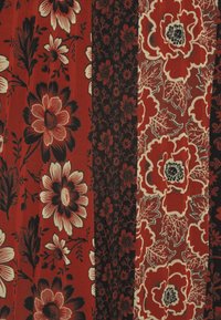 Meerkleurige stof met bloemenpatronen in rood, zwart en crème, met grote bloemen en ingewikkelde bladontwerpen over meerdere verticale secties.