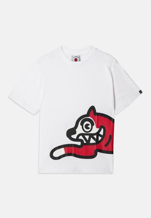 White cotton t-shirt featuring a large red and black graphic of a cartoon-like cat with exaggerated eyes and teeth, positioned on the side.