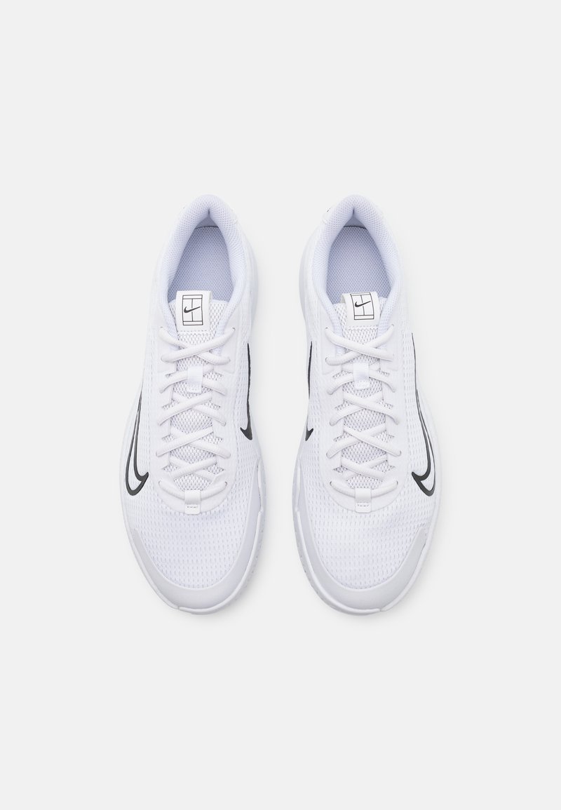 Zapatillas deportivas blancas con parte superior de malla, puntera redonda, acento negro a lo largo del costado y suela texturizada con cordones.