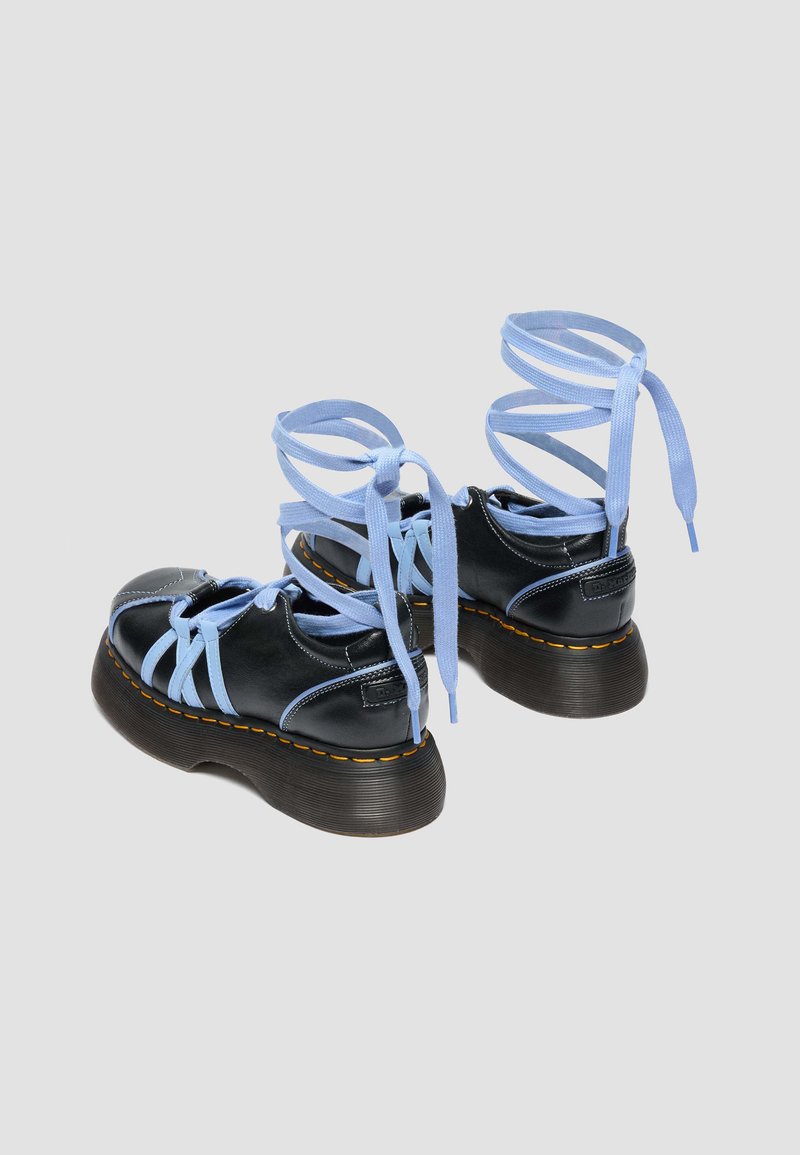 Black platform sandals with thick brown soles, light blue crisscross straps, and wrap-around ankle ties on a gray background.
