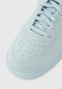 Modro svetel semiš športni copat z luknjanim sprednjim delom, ravnimi vezalkami in enobarvnimi šivi. Ponaša se z diskretno znamko in teksturiranim gumijastim podplatom.