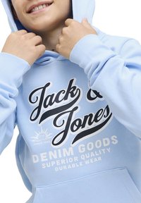 Haut à capuche bleu clair en mélange de coton, doté d'une poche frontale et d'un grand logo en texte noir et blanc avec un graphique de soleil.
