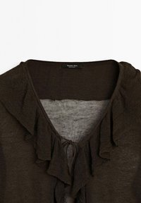 Blouse marron foncé avec un décolleté en V, des accents froncés le long des bords et un tissu léger et texturé. Étiquette de marque visible.
