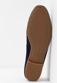 Chaussure en daim bleu marine avec une semelle en caoutchouc marron texturée présentant des motifs ondulés, portant la marque "Gabor" et indiquant "Fabriqué au Portugal".