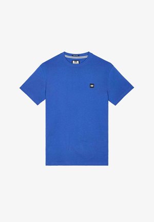 Mėlynas medvilninis marškinėlis su apvalia apykakle, trumpomis rankovėmis ir mažu juodu kvadratiniu ženkliuku krūtinėje. Lygi tekstūra ir laisvas kirpimas.