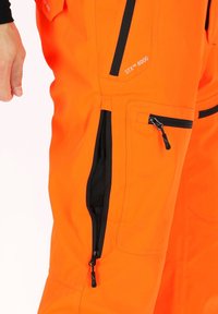 Feloranje waterdichte broek met zwarte ritszakken en accenten. Gemaakt van duurzaam materiaal met een gestructureerde stof en verstelbare ontwerp elementen.