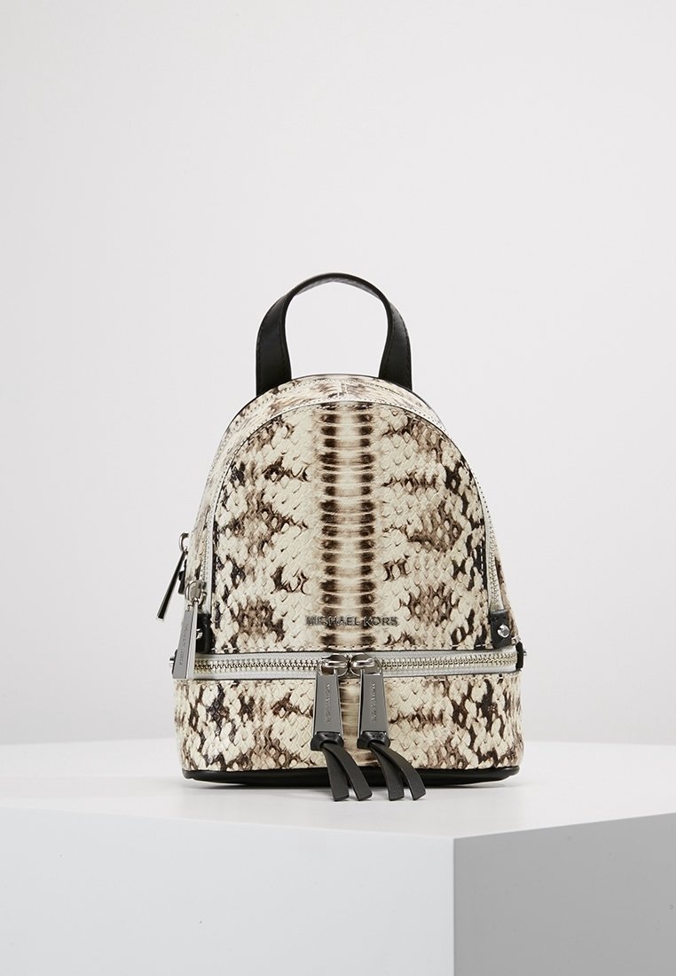 Petit sac à dos avec motif imprimé serpent, présentant des tons beige et marron, des accents noirs et des ferrures en argent. Fermeture à glissière et double bretelles.