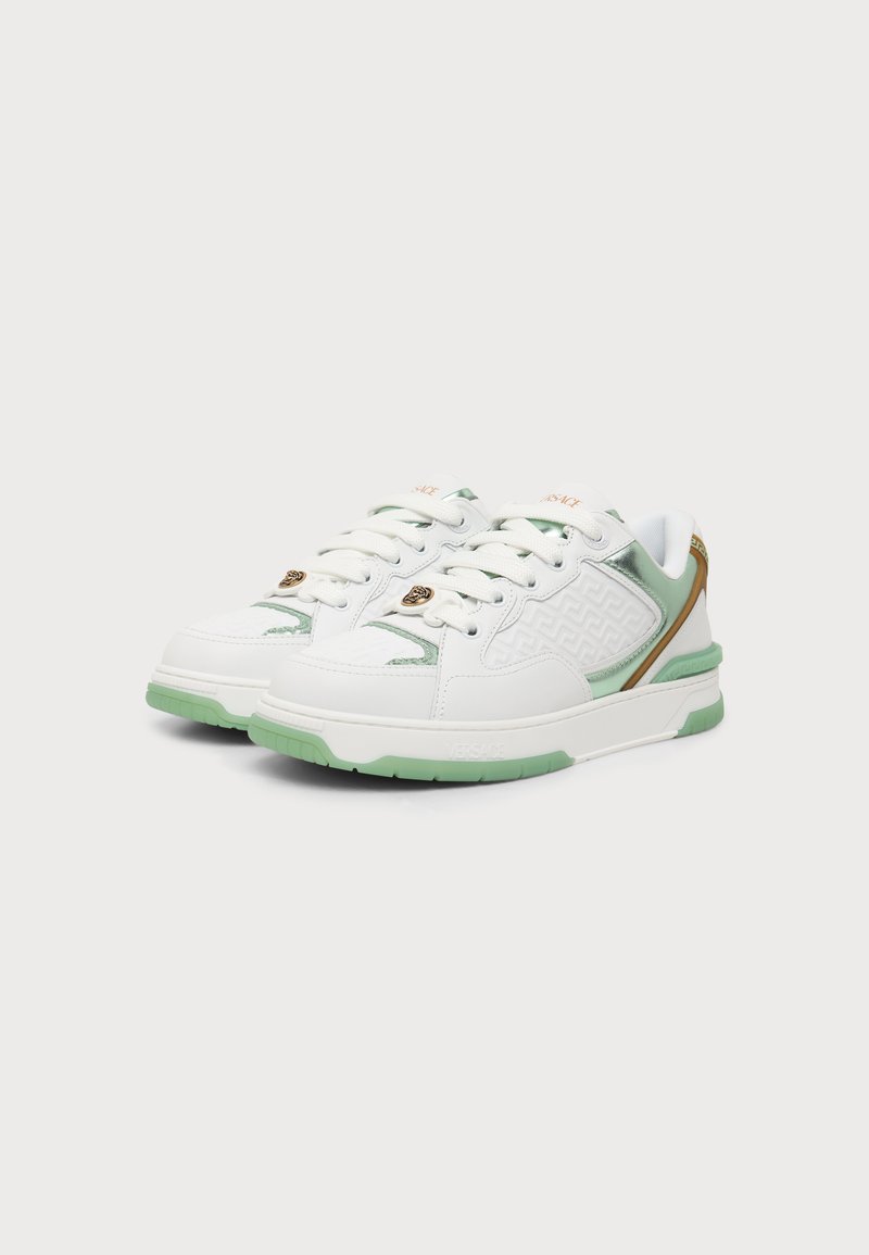 Pair of white sneakers with light green soles, gold accents, and embossed side pattern, positioned side by side on a plain background.