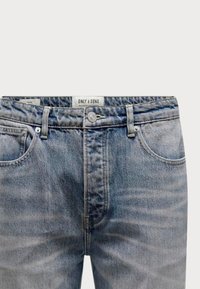 Vaqueros de denim azul claro con un lavado desgastado, bolsillos frontales, una cremallera de botón y una etiqueta en la cinturilla que dice "ONLY & SONS."