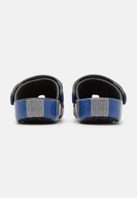 Black and blue plastic sandals with an open back, featuring a textured sole and striped accents in blue and gray across the heel.