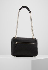 Zwarte handtas met een textuur en reliëflogo's. Het heeft een voorvak met rits en zilveren kettingriemen.