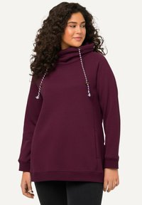 Felpa bordeaux con collo a imbuto, dettagli con coulisse, tasca frontale e polsini a coste. Il tessuto sembra morbido con una texture liscia.