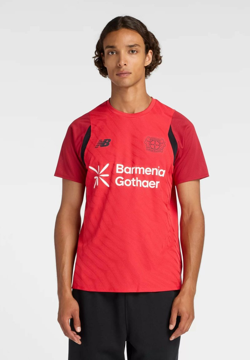 Camiseta deportiva roja hecha de tela transpirable, con un patrón ondulado, detalles en negro en los hombros y logo/texto blanco en el frente.