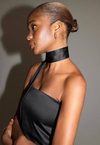 Robe en satin noir avec une bretelle unique et un col tour de cou ; texture lisse avec une silhouette ajustée et un éclat subtil sur un fond neutre.