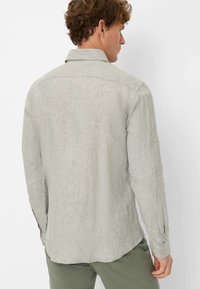 Light gray long-sleeve shirt with a textured fabric, button cuffs, and a classic collar. Tailored fit with a curved hem.