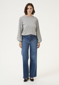 Gray long-sleeve top with pleated balloon sleeves, paired with dark blue wide-leg jeans and black shoes. Simple design, smooth texture.