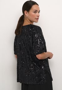 Black sequin top with loose fit, short sleeves, and round neckline. Features a textured surface with a shimmering pattern throughout.