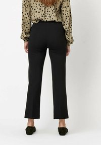 Czarne spódnice z szerokimi nogawkami i wysokim stanem, o gładkiej fakturze, noszone z beżową bluzką w kropki, widok z tyłu, z płaskimi szwami.