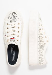 Sneakers platform bianchi con motivi geometrico a disegno ritagliato, lacci bianchi, occhielli dorati e suole interne nere marchiate "Tommy Hilfiger".