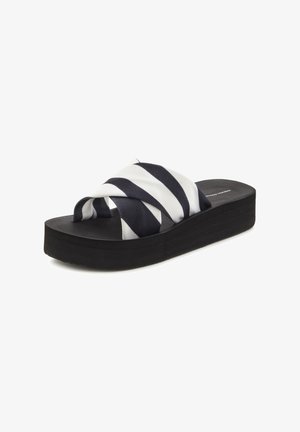 Plattform-Sandalen mit einer schwarzen Gummisohle, ausgestattet mit einem geflochtenen Kreuzgurt in weiß und marineblauen Streifen. Glatte Stoffoberfläche.