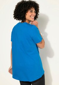 Camiseta de manga corta azul cielo con escote redondo y un largo mayor en la parte posterior. Tejido de algodón suave con un corte relajado y dobladillo recto.