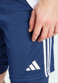 Shorts de sport bleu marine avec une texture lisse, dotés de trois rayures blanches sur le côté et d'un logo Adidas blanc sur l'ourlet.