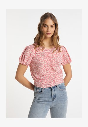 Piros virágmintás blúz puffos ujjal, texturált anyagból és testre szabott kialakítással. Magas derekú világoskék farmernadrággal párosítva.