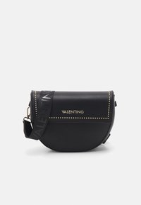 Borsa a tracolla nera in pelle con una forma curva, borchie dorate sulla patta e una tracolla con logo. Texture morbida, design moderno.