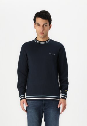 Pull classique à manches longues bleu marine en coton avec un col et des poignets rayés contrastants. Présente un logo brodé sur la poitrine.