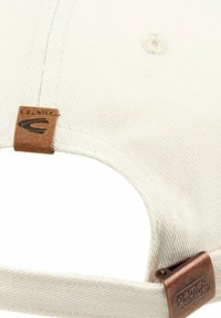 Lys beige baseballcap lavet af struktureret stof, med en brun læderrem med præget logo og en metaljusteringsklips.