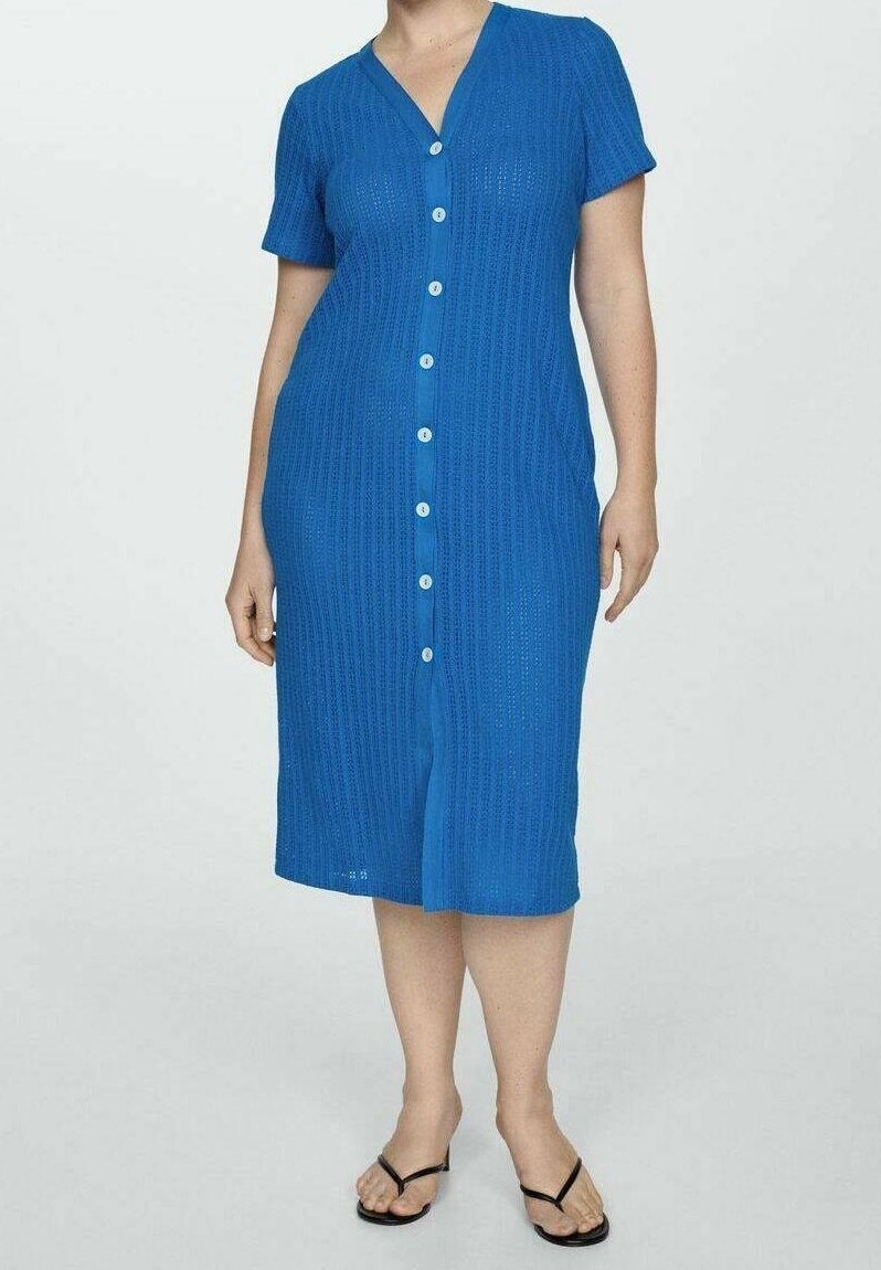 Femme portant une robe bleue à boutons, manches courtes, longueur genou, col en V et des sandales noires.