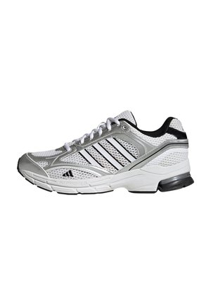 Zapatilla deportiva blanca y plateada con detalles en negro, parte superior de malla, diseño con cordones y suela acolchada mostrada de lado.
