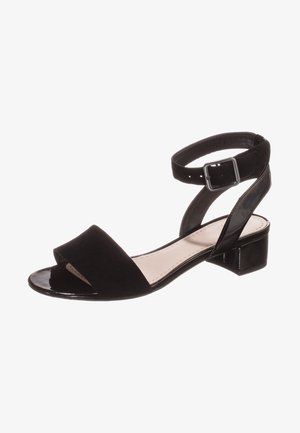 Sandales noires avec une tige en daim, bout ouvert et brides de cheville réglables. Elles disposent d'un petit talon bloc et d'un détail en verni brillant sur la sangle.