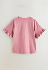 Roosa puuvillane t-särk lühikeste varrukatega, millel on volangäärised. Lihtne ümmargune kaelus ja sile tekstuur. Standardselt istuv ja ühetuuline disain.