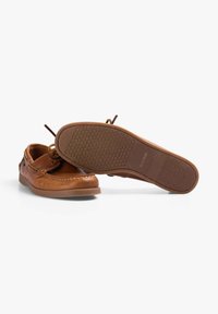 Bruine leren bootschoenen met een gladde afwerking, ronde neus en contrasterende stiksels. De zool is van rubber met een gestructureerd grippatroon.