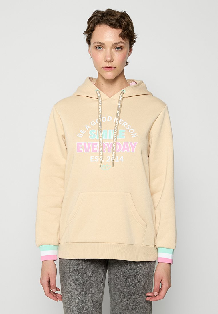 Beżowa bluza z kapturem z przednią kieszenią, z kolorowym napisem "Bądź dobrą osobą" i "Uśmiechaj się każdego dnia." Ściągacze z pastelowymi akcentami.