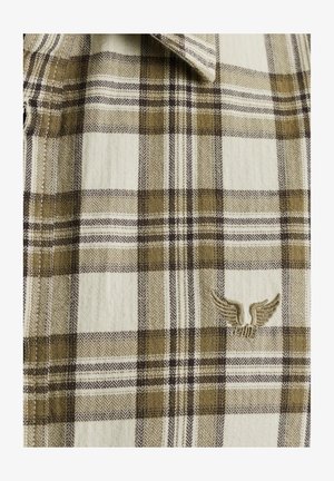 Koszula w kratę w beżowe, brązowe i białe wzory, z teksturowanym wykończeniem i małym haftowanym detalem w kształcie skrzydła przy kołnierzyku.