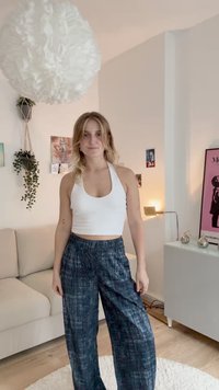 Bela halter crop majica u kombinaciji s širokim plavim hlačama s uzorkom, koje imaju elastični pojas i mekani, teksturirani materijal.