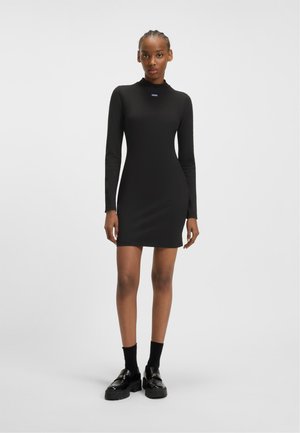 Black long-sleeve dress with a mock neck and slim fit, made of smooth fabric. Features a small logo detail on the chest.
