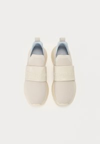 Calvin Klein tenisice od bež mrežastog materijala s širokom bež trakom koja sadrži logotip. Svijetloplava unutrašnjost i teksturirana gumena potpora.