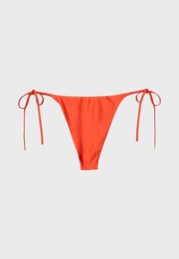 Bas de bikini orange vif avec liens sur les côtés sur un fond clair uni.