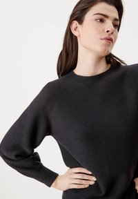 Donkergrijs gebreid sweatshirt met een ronde halslijn en lange mouwen. De stof heeft een gestructureerd patroon en geribde manchetten. Minimalistisch ontwerp.