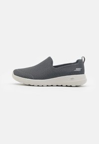 Des chaussures à enfiler en maille grise avec une finition texturée, dotées d'une semelle en caoutchouc blanche et d'une petite languette au talon pour un enfilage facile.